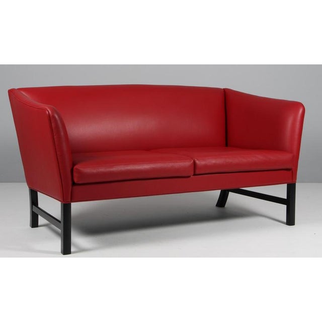 Ole Wanscher two seat sofa with red leather. Legs of black stained oak. Model OW602, made by Poul Jeppesen. This piece is...