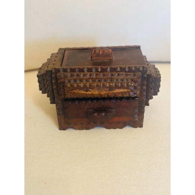 A charming hand-carved wooden box featuring richly textured geometric detailing and a warm, aged patina. Crafted with...