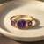Cushion Amethyst Trio Ring in Gold Bold yet refined, this ring features a striking trio of natural amethyst gemstones set...