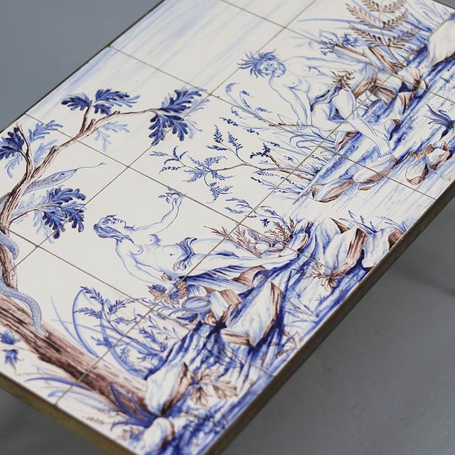 A unique coffee table featuring a brass frame and an exceptionally inlaid tabletop composed of hand-painted tiles. The...