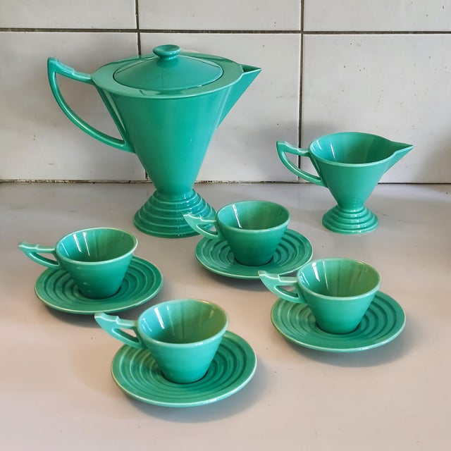 An elegant tea and coffee service comprising a coffee pot, a milk jug, and four cups and saucers in glazed ceramic. The...