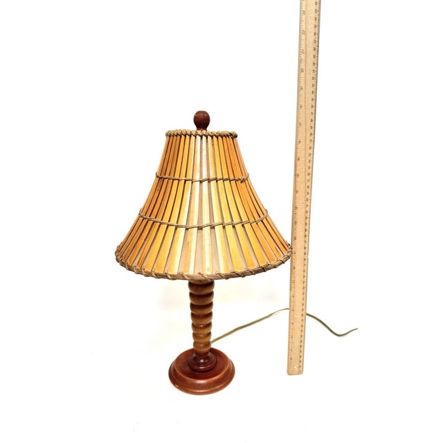 Charming vintage mid-century table lamp featuring a sculptural turned wood base paired with a warm bamboo shade. This...