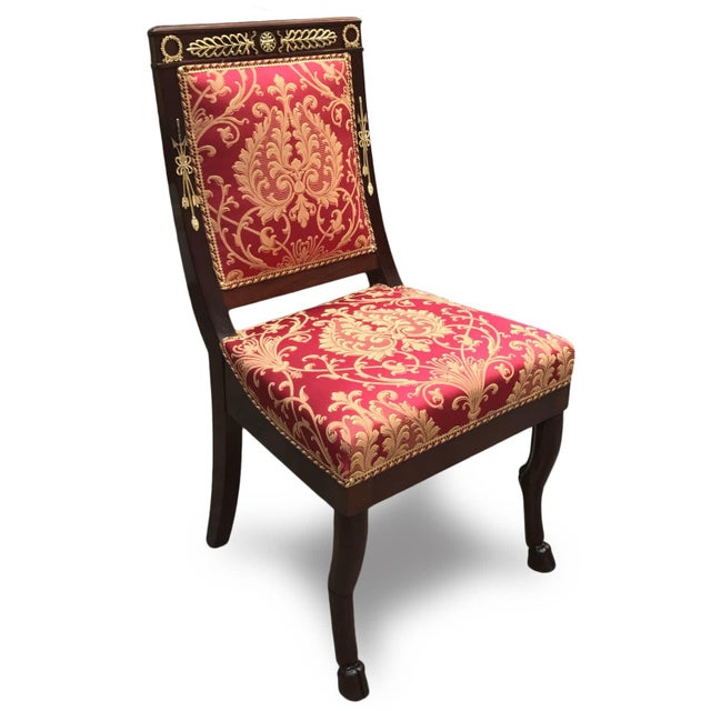 Four Empire mahogany chairs, upholstered in gold damask on red silk, with seats and backrests, all French. The backrest is...