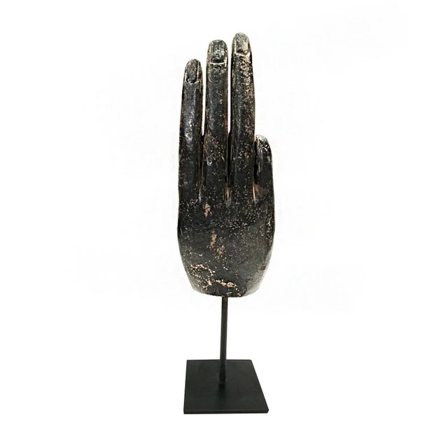 A tabletop sculpture depicting a Buddha hand in a "mudra" or hand position, Indonesia, mid-20th Century. The hand depicts...