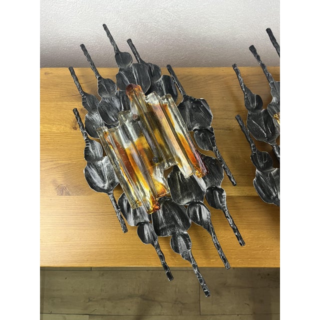 A pair of wall lamps with a wrought iron frame and a thick two-tone glass shade, made in the 1960s. The wall lamps have...
