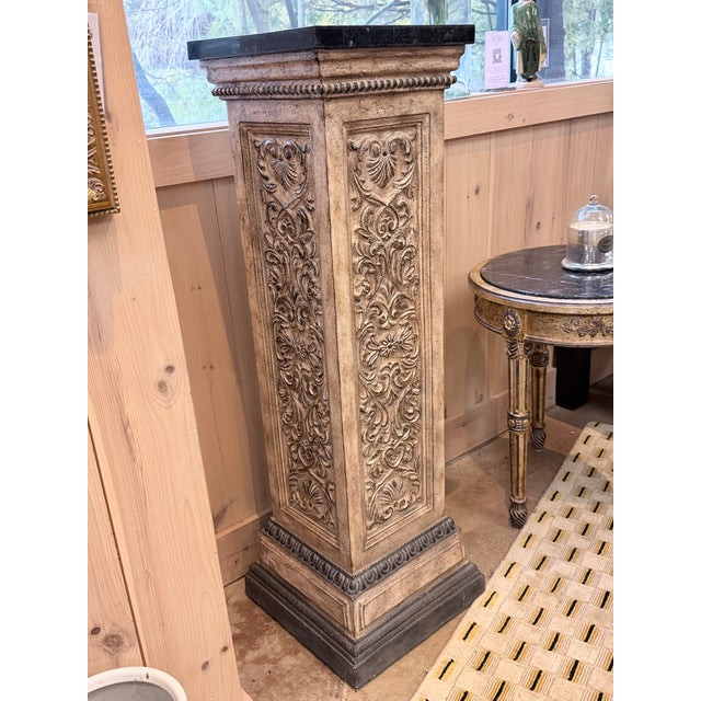 This is an elegant architectural accent piece with strong classical presence. The column features deeply carved scrolling...