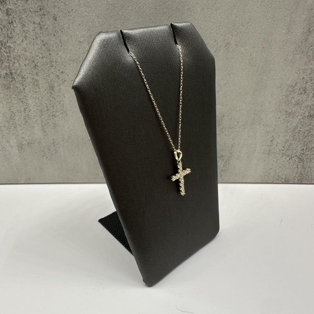 This delicate natural diamond cross necklace in 10kt yellow gold features 0.20 carats total weight of natural IJ VS/SI...