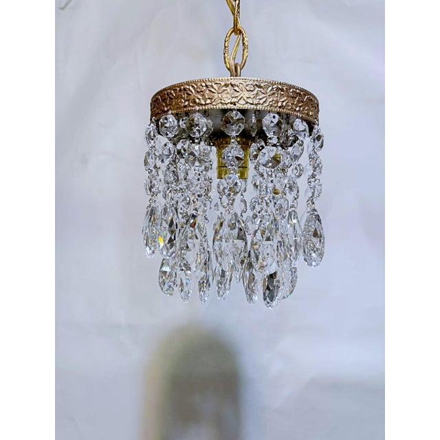 This is a 1960's chandelier with decorative brass rim draped with octagon bead chain and almond cut crystal prisms. It has...