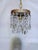 This is a 1960's chandelier with decorative brass rim draped with octagon bead chain and almond cut crystal prisms. It has...