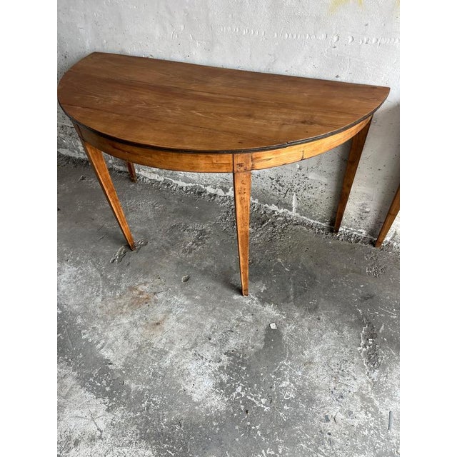 Elegant pair of antique demi-lune console tables crafted in solid wood with beautifully tapered legs and a warm patinated...