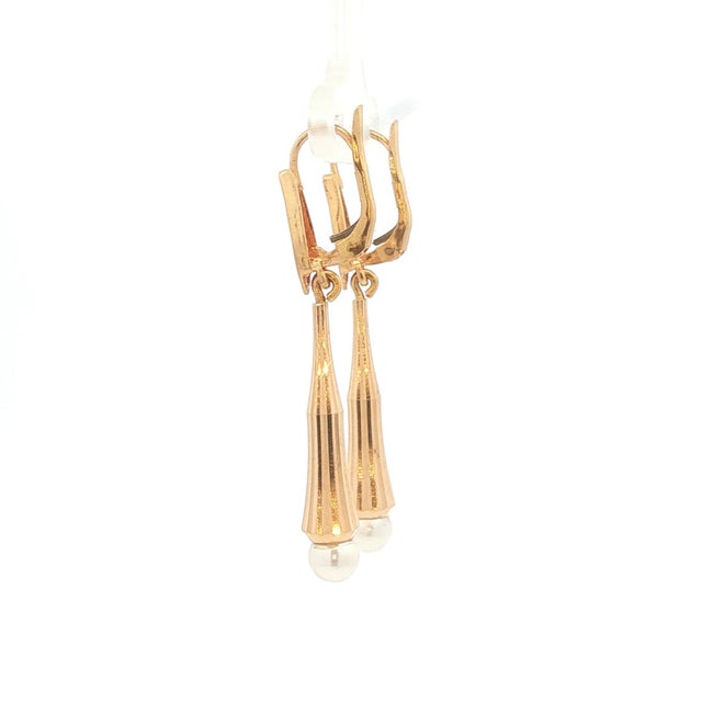 A pair of 18k gold dangle earrings featuring white pearls. The earrings have a sleek, modern design. They measure 1 and...