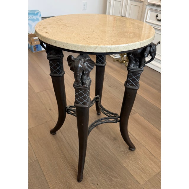 Handsome round marble top end or side table having black metal base with elephant heads at the top of slightly splayed...