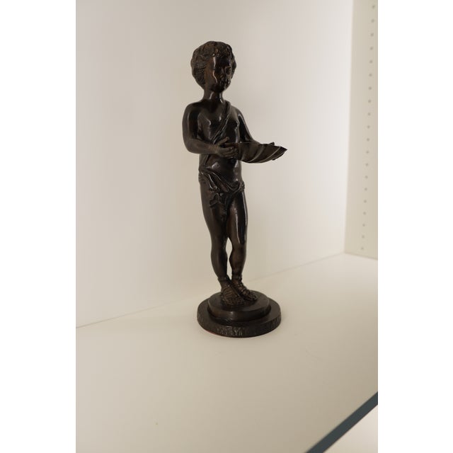 This vintage Italian bronze sculpture depicts a young boy holding a clam shell, rendered with the charming detail and...
