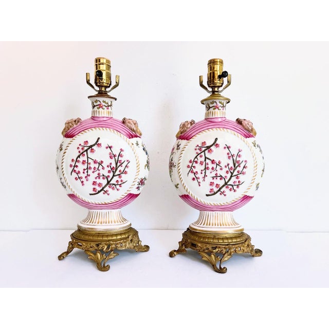 Stunning pair of antique disc-shaped lamps of glazed creamy white porcelain hand painted with bright pink raised cherry...