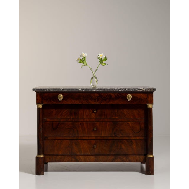 This 1860s Empire chest of drawers with marble top from France is built in richly figured flame mahogany beneath a dark...
