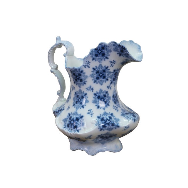 This antique W.H. Grindley flow blue ironstone pitcher features the intricate, geometric "Syrian" pattern, dating...
