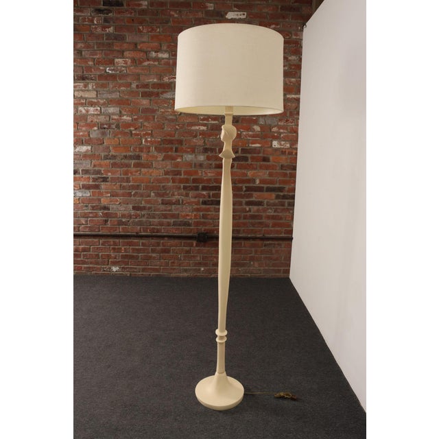 Beige floor lamp styled after Alberto Giacometti's "Tête de femme" design, though sculpted from resin, as opposed to...