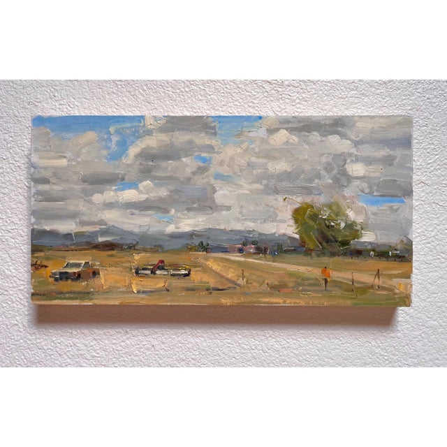 The painting captures a vast landscape under a dynamic sky, where billowing clouds create a sense of movement and depth. A...
