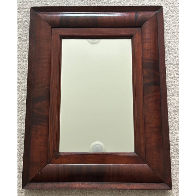 A handsome American Empire wall mirror featuring a rich mahogany frame with broad cushion molding and finely mitered...