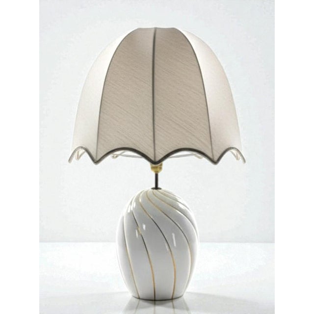 A 1970s Italian table lamp in white glazed ceramic, decorated with gold spiral lines, attributed to Tommaso Barbi, a major...