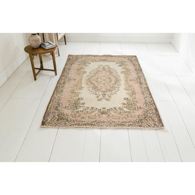 This is a vintage Turkish Oushak rug from the Mid 20th Century. The piece was hand-knotted.