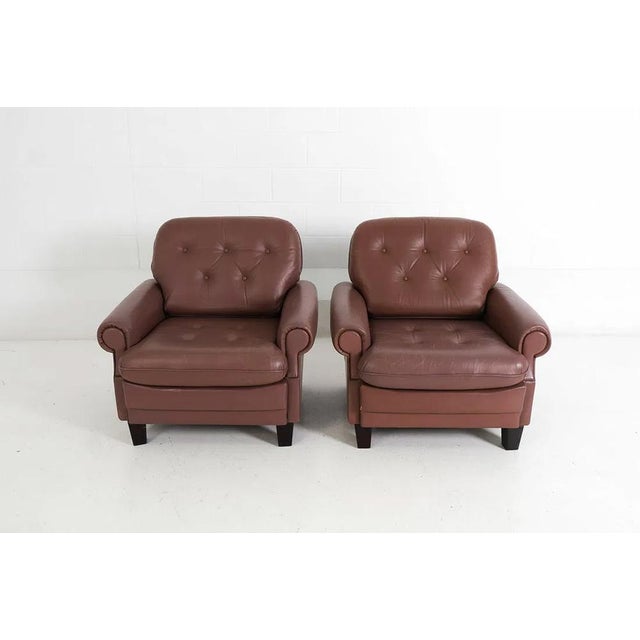 A pair of relaxing tufted leather lounge chairs. The chairs are of northern European (German) origin and are upholstered...