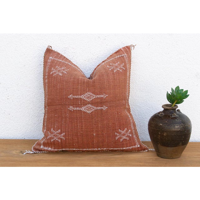 Bold X-shaped crosses mark each corner of this handcrafted Moroccan cactus silk pillow, framing a central ladder-like...