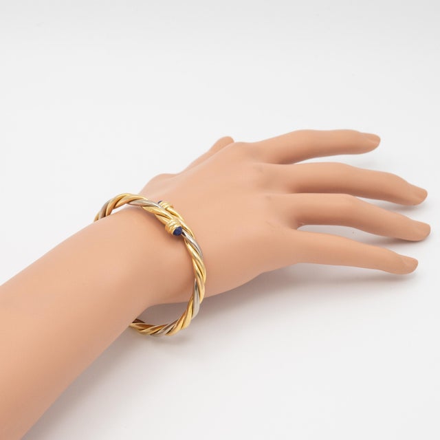 A rare and collectible Cartier torque bangle expertly crafted in 18K yellow and white gold, completed with deep blue lapis...