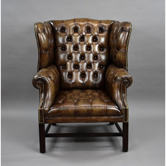 An impressive antique circa 1920 Chesterfield wingback armchair, upholstered in deep-buttoned hand-dyed leather with a...