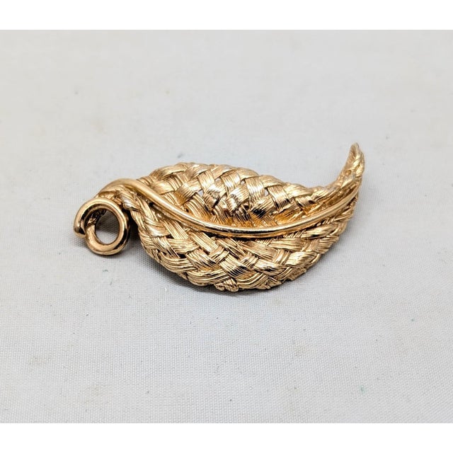 1960s goldtone "woven" leaf with curled stem brooch with security clasp. Marked "NAPIER©" on the back near the tip of the...