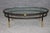 This handsome contemporary oval coffee table, combining dark-finished steel, warm brass accents, and a substantial clear...
