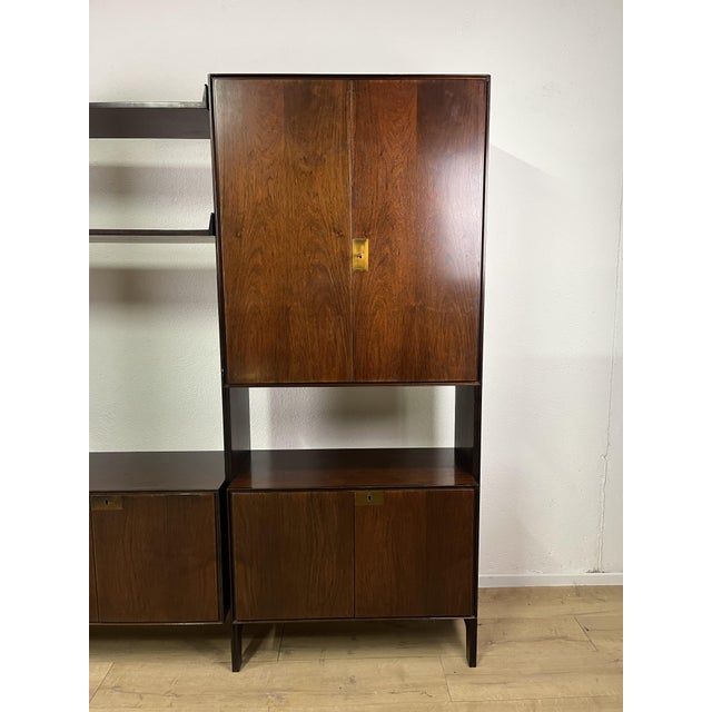 Freestanding teak bookcase with brass fittings, consisting of four uprights, three shelves, and five closed elements,...