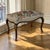 A French Louis XV walnut footstool featuring the fluid, curving lines characteristic of the style. The shaped apron flows...