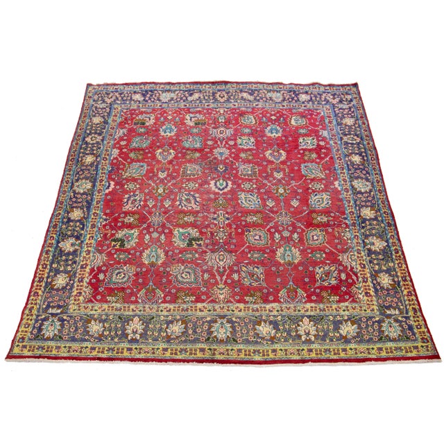 This 1960s Persian rug hand-knotted in wool has a red field with multicolor accents in an all-over floral pattern. This...