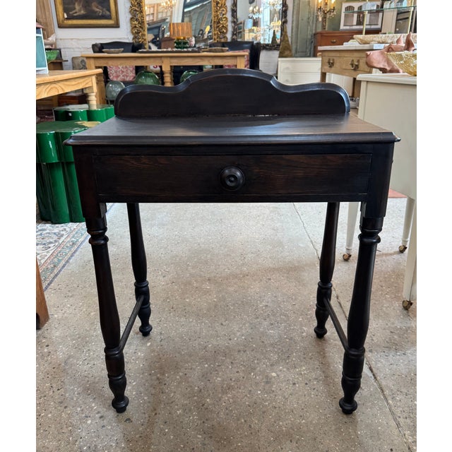 A charming vintage side table in a rich ebonized finish that highlights the wood grain. It features a single drawer with a...