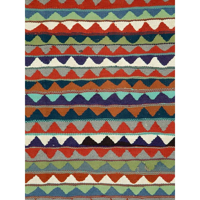 A Mid-20th century Persian flatweave kilim distinguished by its lively sequence of horizontal bands composed of repeating...
