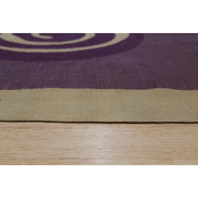 This purple wool rug features a flat weave construction in the Kilim style. Sourced from China, the piece displays a color...