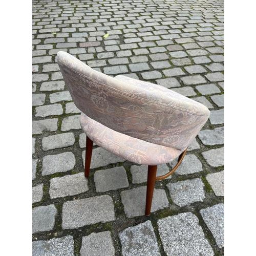 A finely crafted upholstered chair with a curved backrest, elegantly combining comfort and Danish craftsmanship. The...