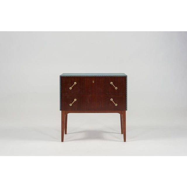 Very beautiful, modern commode from the 1950s in mahogany veneer with teak base, 2 drawers with brass handles. The commode...