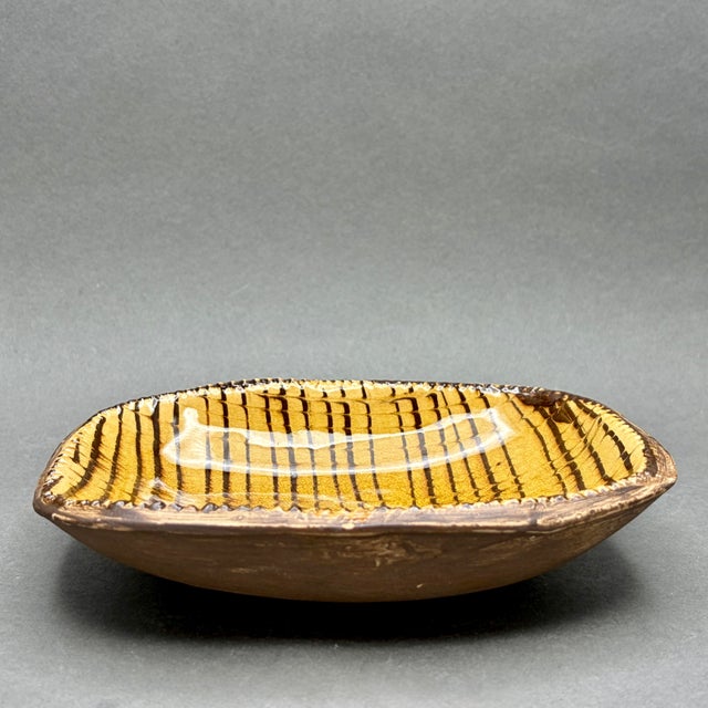 • Handmade studio art pottery dish with rounded rectangular form and irregular rim. • Mid-century design, likely...