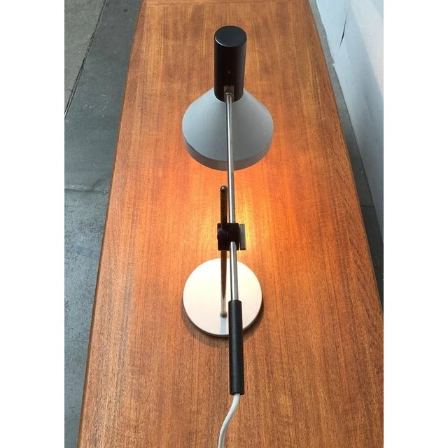 Minimalist Mid-Century table lamp. Simple table lamp in gray and black. The umbrella shows a classic funnel shape. The...