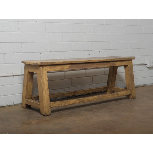 A wooden bench defined by its simple, functional form and quiet presence. The piece is constructed with a rectangular top...