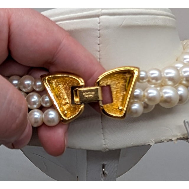 1980s 3-strand goldtone strands of faux-pearl with molded pink flower center with a cluster of faux-pearls at the center...