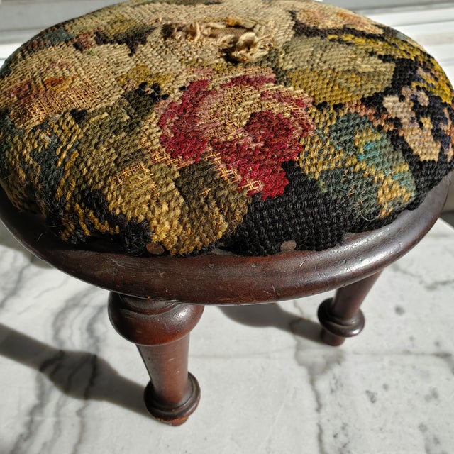 An exceptional antique footstool featuring a beautifully, hand-stitched wool gros point top with a detailed floral motif....