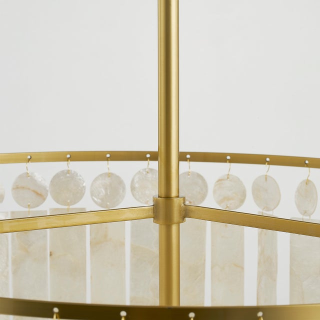 Gorgeous layers of Capiz shell, in alternating circles and rectangles, dangle from an Aged Brass frame for a sophisticated...