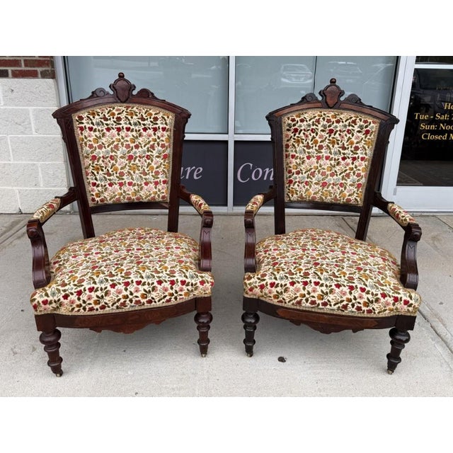 This pair of antique Eastlake parlor chairs features richly toned walnut frames with carved cresting, shaped arms, turned...