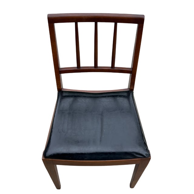 Handsome vintage wood side chair featuring a warm, dark-stained frame and a sleek black upholstered seat. The chair has a...