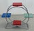A distinctive Functionalist plant stand featuring a circular chrome-plated tubular steel frame and four colourful wooden...