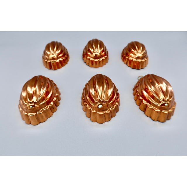 A set of six vintage copper molds, each cast in a deeply fluted, gadrooned oval form and finished with a tin lining and...