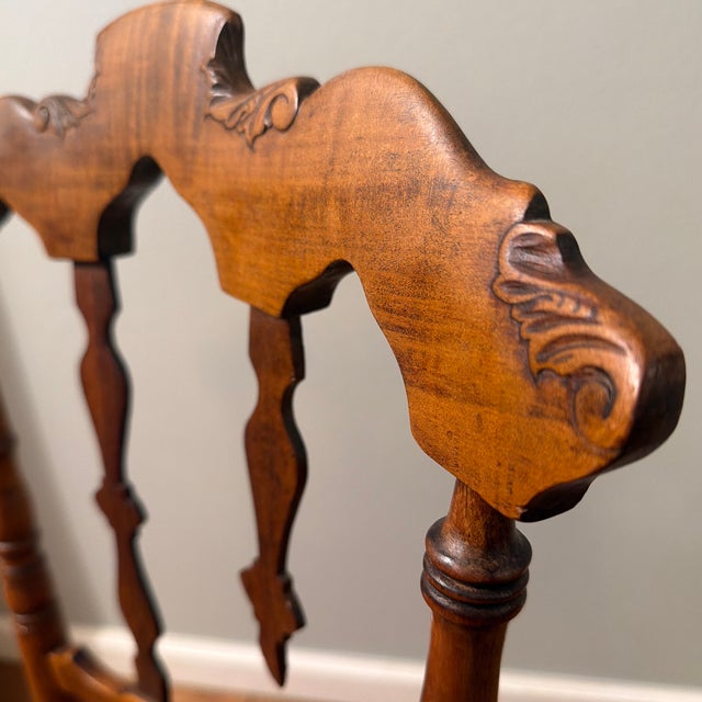 This is a Queen Anne or early American style chair with carved arch along the top crest rail. The turned supports...